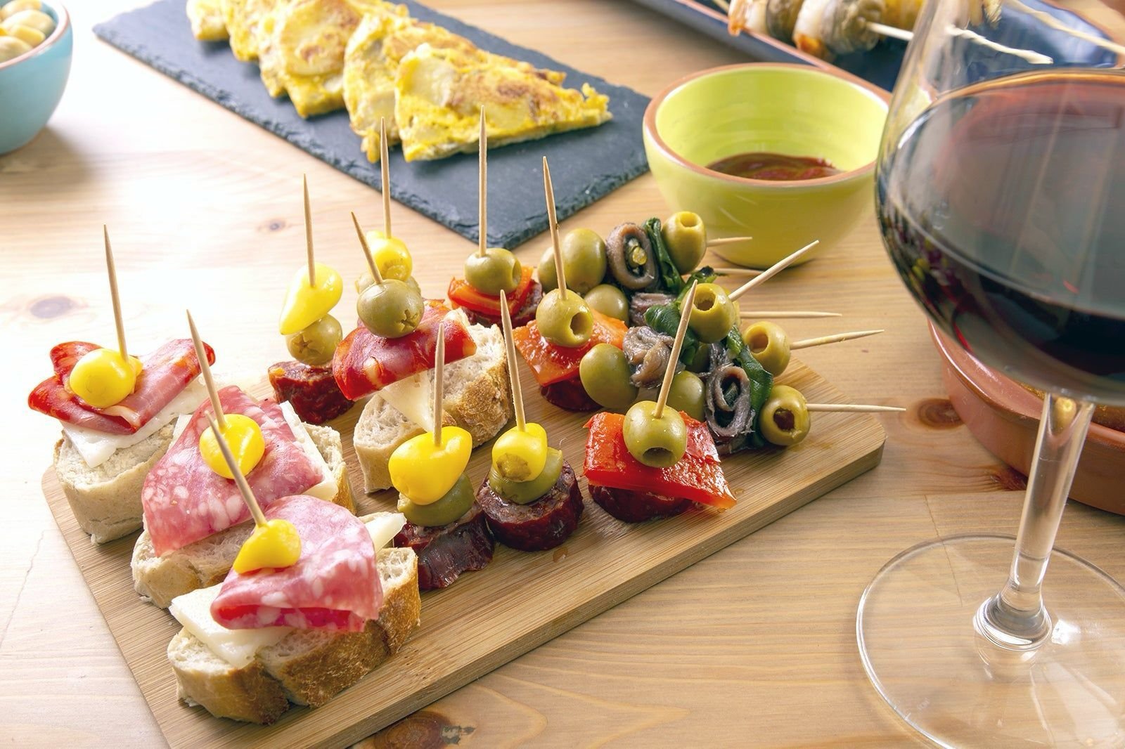 Surtido de pinchos y tapas variadas con vino tinto en una barra de bar tradicional en España.